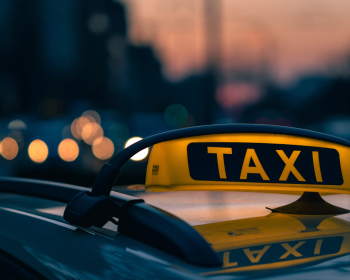 Close-up shot of a taxi sign in the warm colours of sunset with bokeh lights in the background